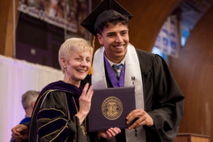 McNair Scholar, Juan Mejia Beltran, poses with President Sue Thomas for a photo at the December 2024 Commencement.